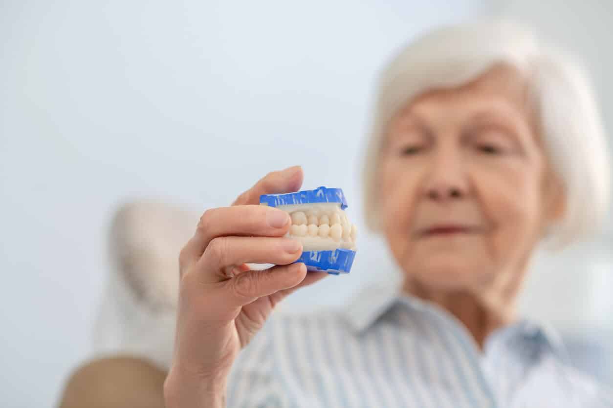 Senior woman holding a denture.