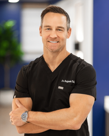 Dr Tolley in black medical scrubs standing.