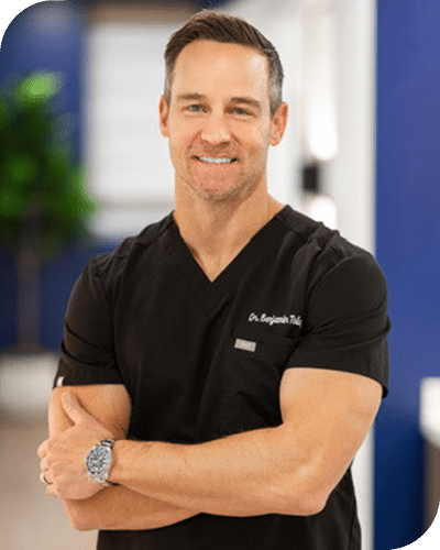 Dr Tolley in black medical scrubs standing.